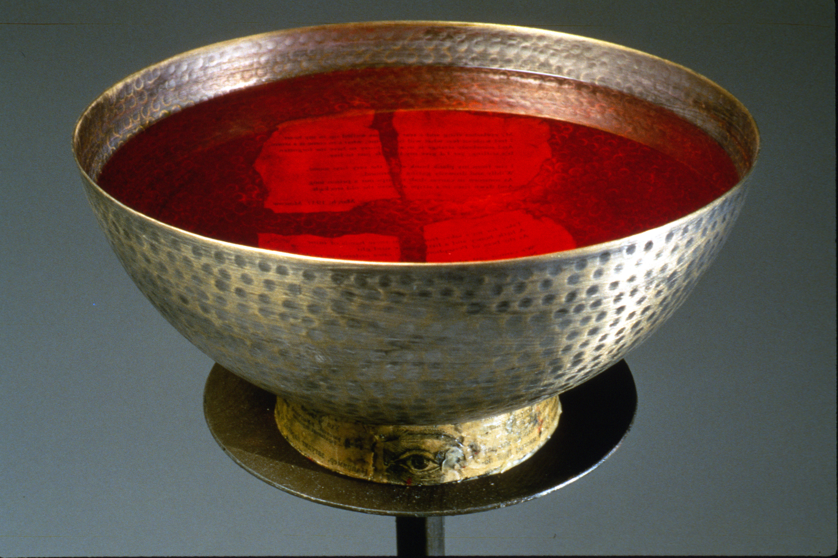 Sacristy Bowl 2. detail. Hammered metal, paint, wax, colored water. Poem in bowl by Osip Mandelstaam. 10" round x 5" bowl, 42" iron, barbed wire stand. 1999